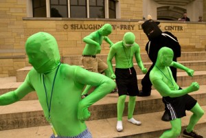 Four green men and someone in a bull costume dance on the steps of O'Shaughnessy-Frey Library. (Aaron Hays/TommieMedia)