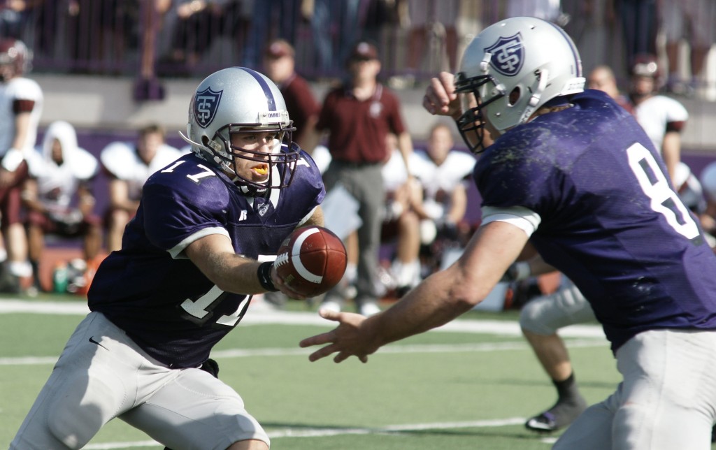 101009_Football_Kruger_002 Quarterback Dakota Tracy hands the ball off to running back Ben Wartman. The Tommies ran the ball for a total of 330 yards and 6 touchdowns. (John Kruger/TommieMedia)