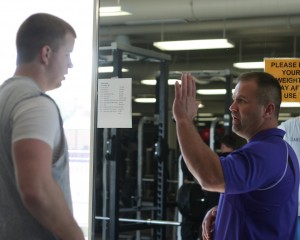 St. Thomas strength and conditioning coach Ty Stenzel gives advice to a football player in the weight room on how to complete a lift better. (Jake Swansson/TommieMedia)