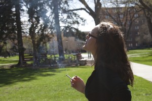 <p>A St. Thomas student smokes a cigarette an appropriate distance from the dorms so it doesn't affect residents. (Laura Landvik/TommieMedia)</p>
