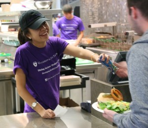 <p>Sophomore Scooter's employee Chau Bui hands a Ranch dressing packet to a customer to accompany his side salad. The healthier side options will cost Scooter's more than the potato chips they offered in the past, Gayle Lamb, operations manager for dining services, said. (Laura Landvik/TommieMedia)</p> 