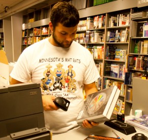 <p>Freshman Sam Larence scans books purchased by students at the St. Thomas book store. Textbooks are just one of the many factors that go into student loans. (Kayla Bengtson/TommieMedia)</p> 