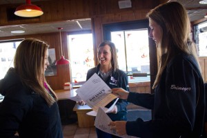 Junior volleyball player Paige Brimeyer hands senior Caitlin Goodwin a voucher during the volleyball team's Davanni's fundraiser. (Rita Kovtun/TommieMedia)