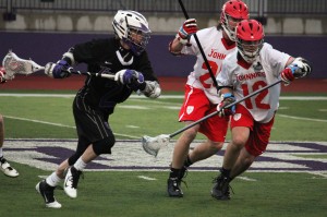 Attackman Dan Burke runs the ball up the field past two Johnnie defenders in an April battle with St. John's. (Morgan Neu/TommieMedia)
