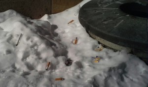 Snubbed cigarettes lay littered on the snow where an ashtray used to be. Although the tobacco ban at St. Thomas has been successful overall, some community members have continued their tobacco use.  (Rebecca Mariscal/TommieMedia)