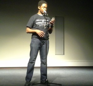 Junior James Mite, leader of the Black Empowerment Student Alliance, wears his "Black History is American History" shirt as he performs one of his poems during the slam poetry contest on Friday night. BESA held a "Black Out Day of Solidarity" on Friday to raise awareness for Black History Month. (Rebecca Mariscal/TommieMedia)