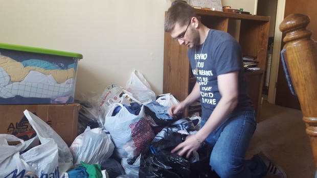 Junior Adam Weinzetl goes through bags of donated clothes. Weinzetl worked with junior Maria Post to head this year's Corporal Works of Mercy Project. (Meghan Meints/TommieMedia)