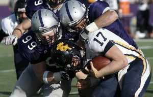 Two St. Thomas defenders sack Carleton's quarterback. The Tommie defense will face a powerful 