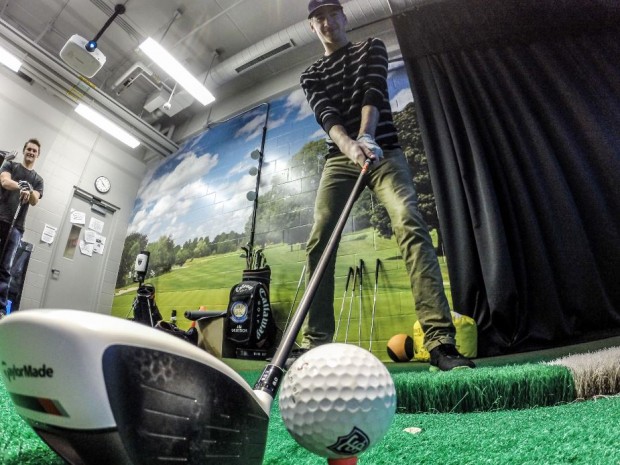Sam Palmisano and Bennet Schroeder practice with a golf simulator last year. Men's golf made a 16-stroke comeback Tuesday to  win the Golfweek Preview tournament. (Jake Remes/TommieMedia)