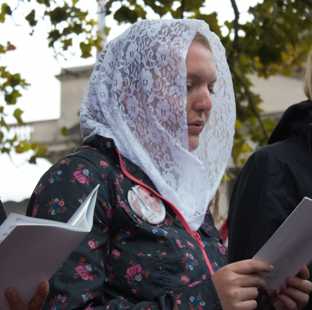 St. Catherine student Mary Lu Kavanagh-Beltman reads from the booklet outlining Sunday's papal Mass.  Kavanagh-Beltmanwore was one of many attendees who wore a veil to the Mass. (Grace Pastoor/TommieMedia) 