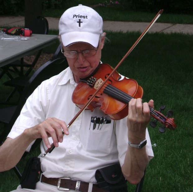 The Rev. David Smith plays the violin at a retirement party. Smith arrived at St. Thomas in the 1950s.