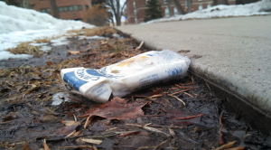 An empty cigarette carton lies next to the sidewalk entering campus. Some students are still smoking on campus despite a community-enforced smoking ban. (Simeon Lancaster/TommieMedia)
