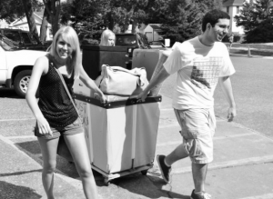 I pull one of two bins filled with dorm decor through the parking lot on freshman move-in day fall 2011 with a little help from a move-in volunteer. I've learned a lot since then and came up with a list to share with incoming freshmen. (Courtesy of Sandra Warfield)