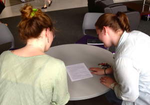 Freshman Meredith Heneghan and sophomore Madelyn Larsin look over their "Goodbye to all of that: St. Thomas" document. The two students were members of FENCOM, the organization on campus that drafted the piece. (Kayla Bengtson/TommieMedia)