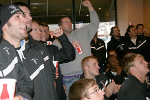 Defensive Coordinator Wallie Kuchinski, center, pumps his fist in celebration Sunday at Davanni's after ESPN announced that St. Thomas is the No. 1 seed in its region for the Division III NCAA tournament. (Miles Trump/TommieMedia)