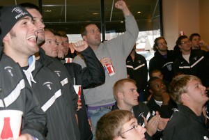 Selection-show Defensive Coordinator Wallie Kuchinski, center, pumps his fist in celebration Sunday at Davanni's after ESPN announced that St. Thomas is the No. 1 seed in its region for the Division III NCAA tournament. (Miles Trump/TommieMedia)