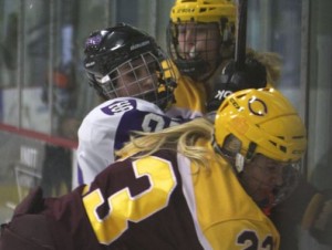 St. Thomas Forward Karina Marette crashes against the glass between two Cobbers. Marette is one of seven senior returning to the team. (Andrew Brinkmann/TommieMedia)