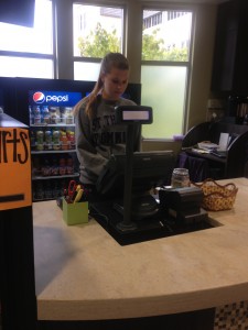 A student employee runs the Beaker's Coffee Cart cash register on its first day of business of the fall 2013 semester.  Beaker's held its grand reopening Wednesday  after renovations were delayed by more than a month. (Johnnay Leenay/TommieMedia) 