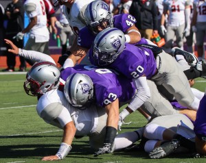 St. Thomas defensive linemen Micah Hausman and Anthony King-Foreman take down Hamline quarterback Justice Spriggs with help from St. Thomas defensive back Jack Dwyer. Saturday's halftime score was 43-20 with the Tommies in the lead. (Carlee Hackl/TommieMedia) 